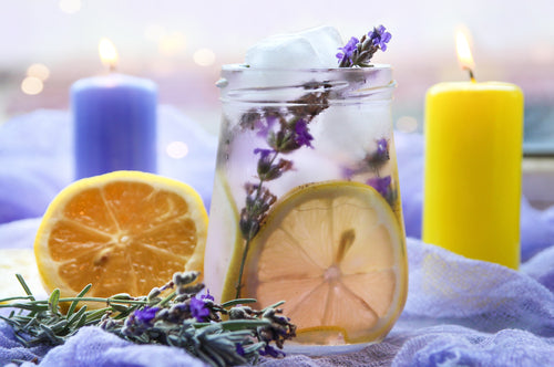 Tea in a mason jar surrounded by fruit and candles
