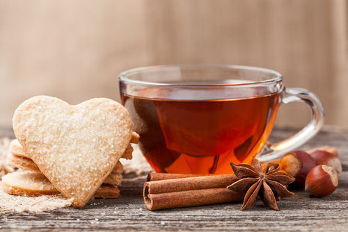 heart shaped cookies and tea in a cup surrounding cinnamon 