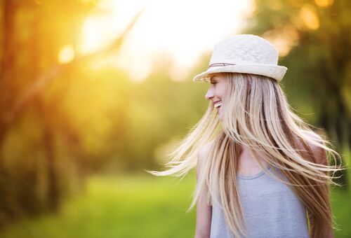 Blonde woman smiling and spinning her hair on a sunny day